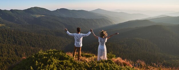 Paar houdt handen op de top van de berg