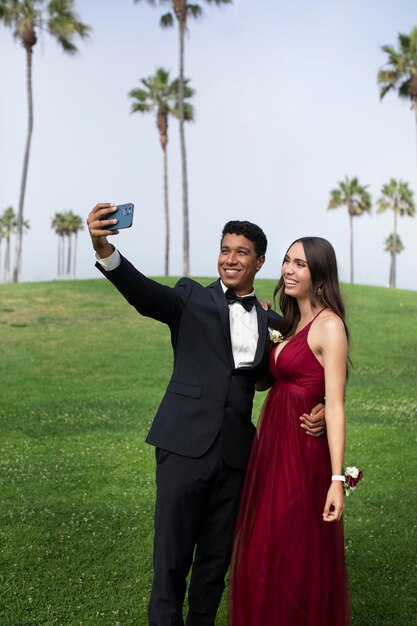 Paar in afstudeerbalkleding die een selfie maakt