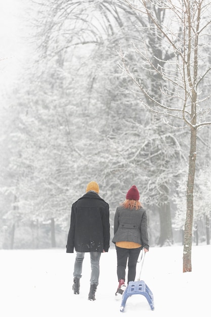 Gratis foto paar in de sneeuw slepen een slee