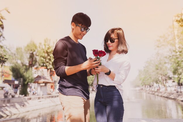 Paar in een park met rozen in handen en zonnebril