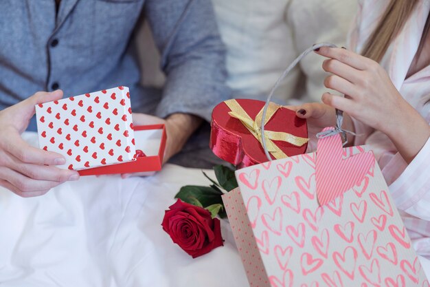 Paar in pyjama zittend op bed met geschenken