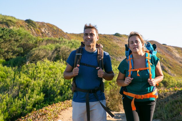 Paar kampeerders wandelen buiten, wandelen op pad van het platteland, wegkijken. Vooraanzicht. Natuur en recreatie concept