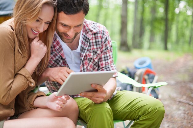 Paar kamperen in het bos. Echtpaar met behulp van een digitale tablet in het bos