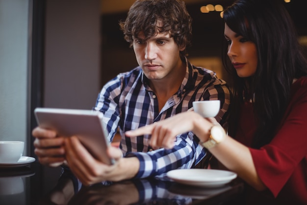 Paar met behulp van digitale tablet terwijl het hebben van koffie