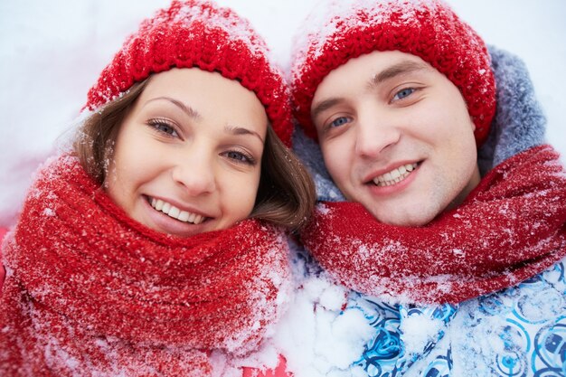 Paar met rode wollen muts in de sneeuw