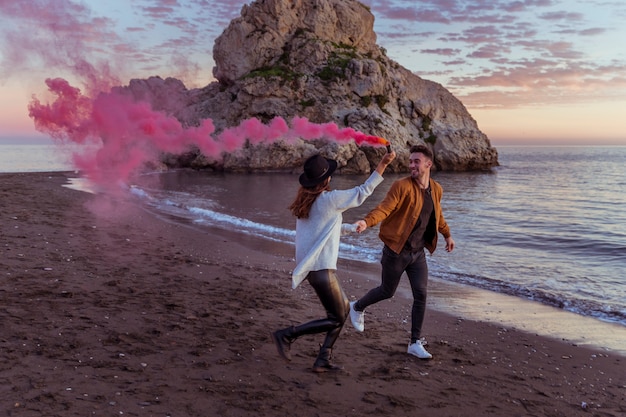 Gratis foto paar met rookbom die op overzeese kust lopen