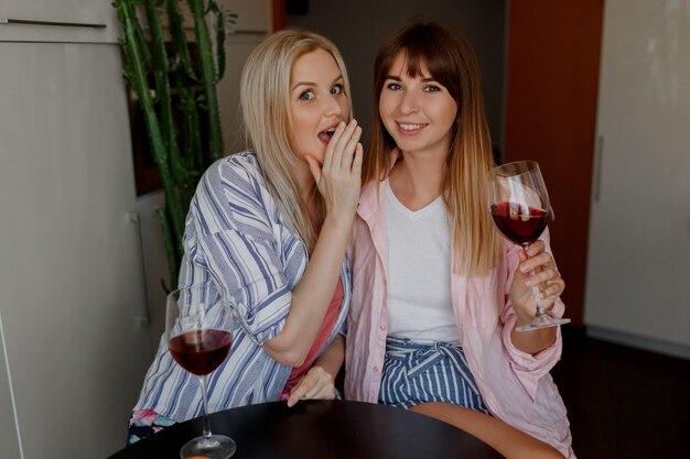 Paar mooie vrouwen die thuis wijn drinken. Pyjama's aan.