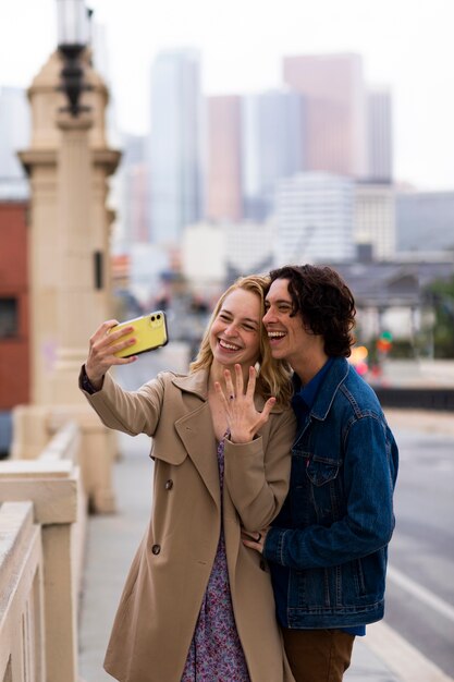 Paar nemen selfie samen buitenshuis met verlovingsring