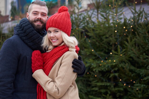 Paar omarmen naast kerstboom