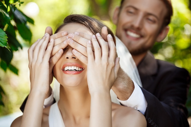 Paar pasgetrouwden glimlachen. Bruidegom die de ogen van de bruid behandelt met handen.