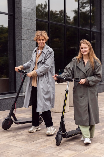 Paar poseren met elektrische scooters buitenshuis