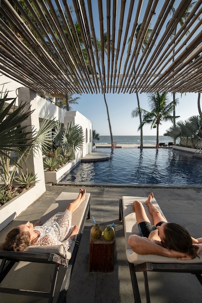 Paar praten en kokosmelk drinken bij het zwembad tijdens vakantie