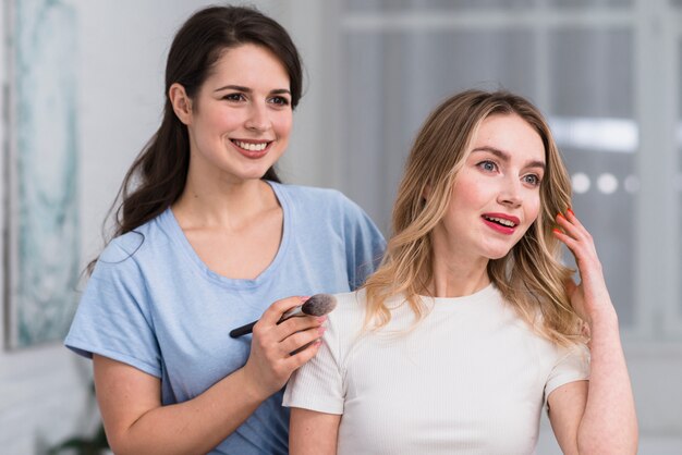 Paar van glimlachende mooie vrouwen in make-upproces.