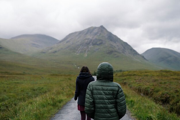Paar van vrienden die door de regen in Glen Etive, Schotland lopen