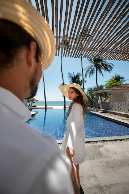 Gratis foto paar wandelen bij het zwembad tijdens vakantie