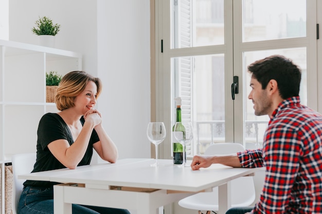 Gratis foto paar wijn drinken en praten aan tafel