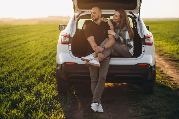 Paar zitten in de achterkant van de auto in het veld