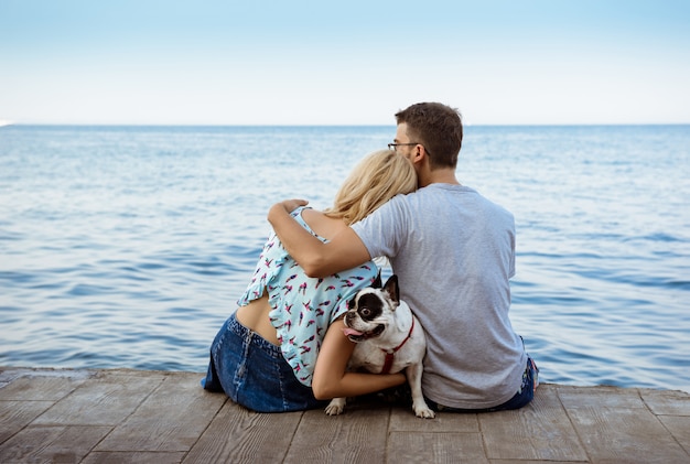 Paar zitten met Franse bulldog in de buurt van de zee