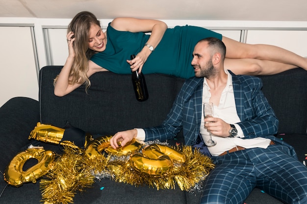 Gratis foto paar zittend op de bank met champagne op feestje
