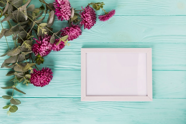 Paarse bloemen met leeg frame op blauwe houten tafel