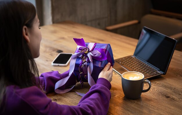 Paarse geschenkdoos in handen van een vrouw in een paarse trui