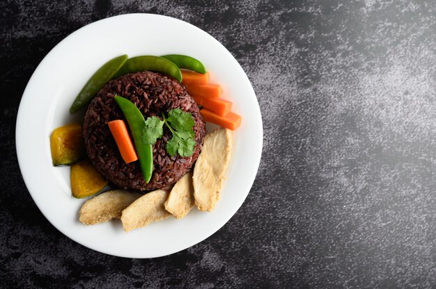 Paarse rijstbessen gekookt met gegrilde kipfilet. Pompoen, wortelen en muntblaadjes in een schaaltje, schoon voedsel.