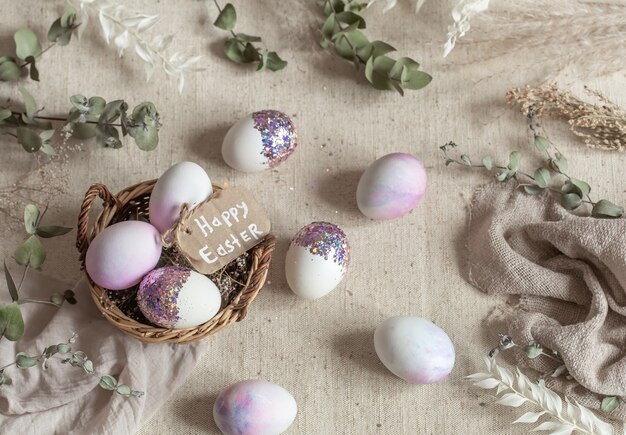 Paasstilleven met eieren versierd met pailletten in een rieten mand. Vrolijk Pasen-concept