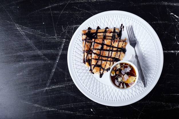 Pannenkoeken in een witte plaat met chocoladesiroop en thee.