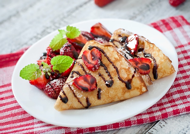 Pannenkoeken met aardbeien en chocolade versierd met muntblad