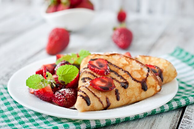 Pannenkoeken met aardbeien en chocolade versierd met muntblad
