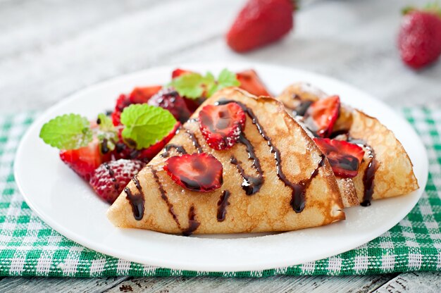 Pannenkoeken met aardbeien en chocolade versierd met muntblad