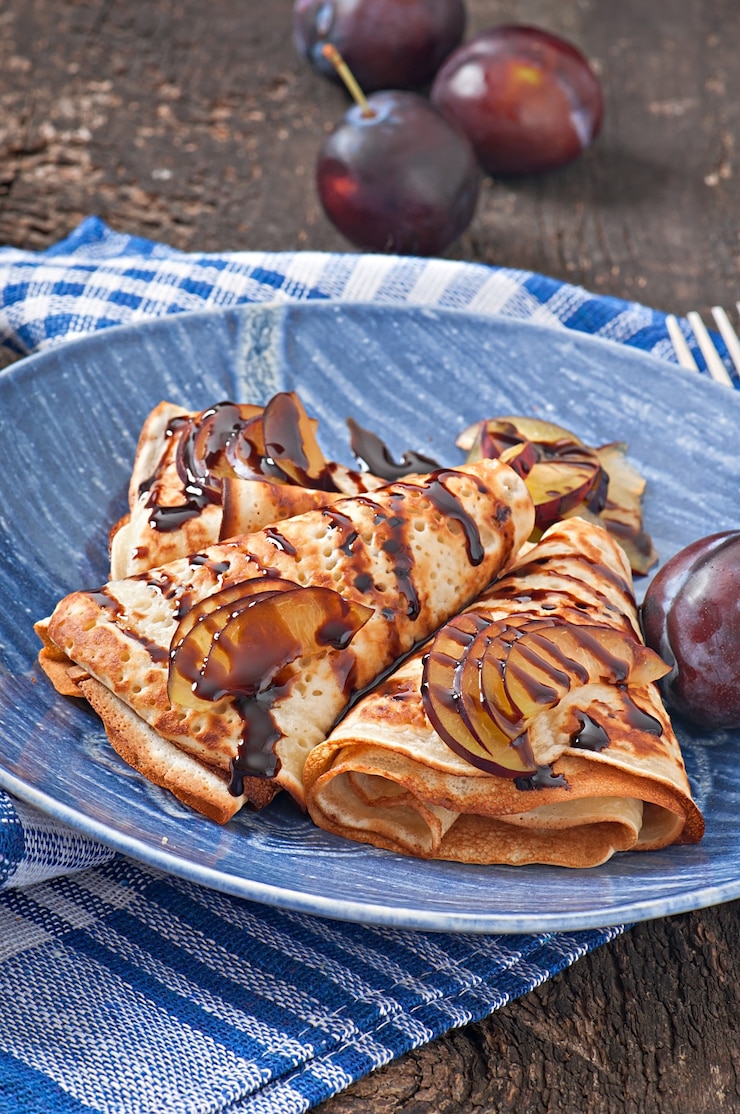 Gratis Foto pannenkoeken met chocoladesiroop en pruimen