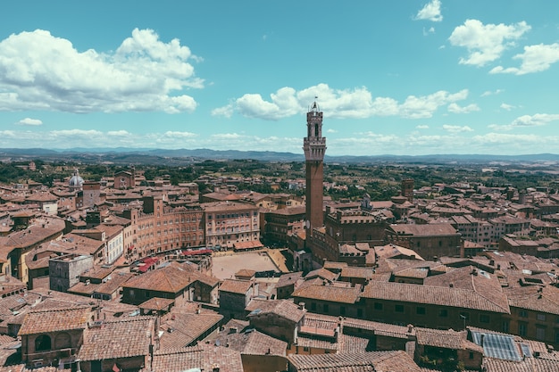 Panoramisch uitzicht over de stad siena met piazza del campo en de torre del mangia is een toren in de stad vanaf de kathedraal van siena (duomo di siena). zonnige zomerdag en dramatische blauwe lucht