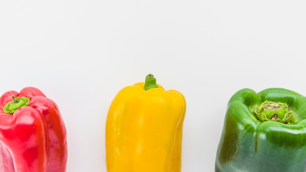 Gratis foto panoramisch zicht op rood; gele en groene paprika's op witte ondergrond