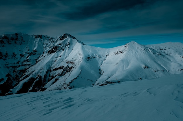 Panoramische opname bovenop een met sneeuw bedekte berg onder bewolkte hemel