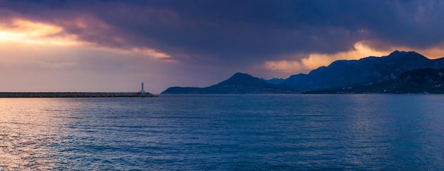 Gratis foto panoramische opname van de zee omringd door kliffen onder een bewolkte hemel in de avond