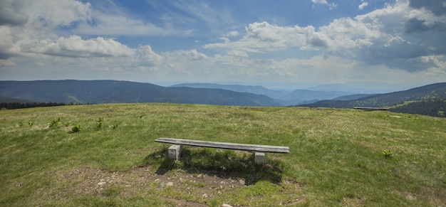 Panoramische opname van een lege houten bank in het veld bij het Ribnica-meer in Slovenië