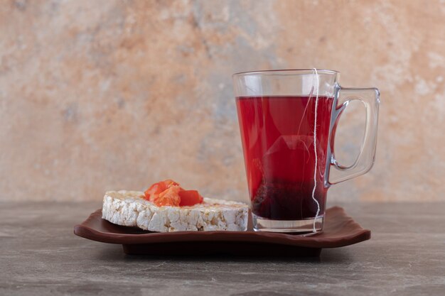 Pap met plakjes tomaat in een glas op een houten plaat, op het marmeren oppervlak