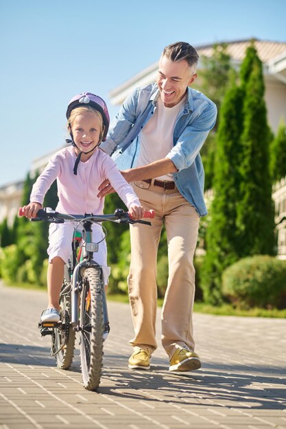 Papa fietst terwijl zijn dochter erop zit