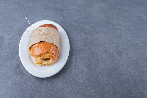 Papier gewikkeld zoet brood op bord, op het marmer.