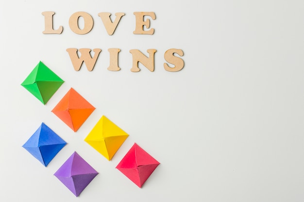 Gratis foto papieren origami in lgbt-kleuren en liefde winnen woorden
