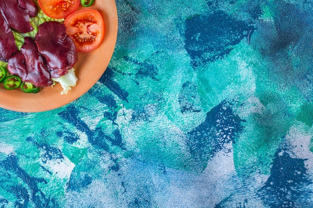 Gratis foto paprika, tomaten, sla en kippenafval op een kleiplaat