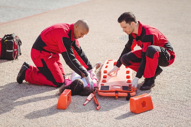 Paramedici die gewond meisje op een bord zetten