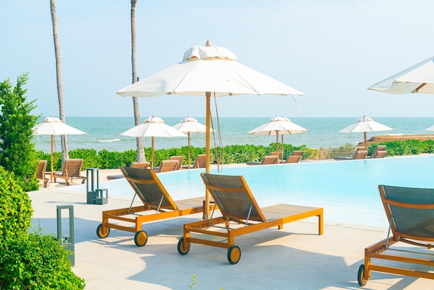 Paraplu met bed zwembad rond zwembad met oceaan zee achtergrond - vakantie en vakantie concept