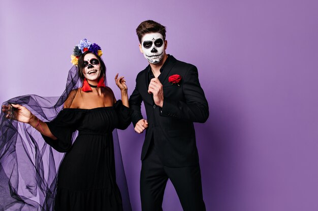 Parmantige mannen en zijn vrouw in zwarte outfits hebben plezier en dansen op een Halloween-feest.