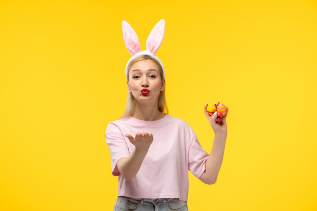 Pasen mooi blond schattig meisje met roze konijnenoren en rode lippenstift die kusjes verzendt