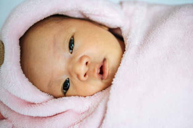 pasgeboren baby slaapt op de deken en opent de ogen
