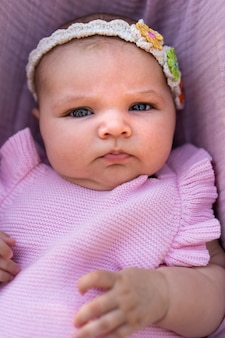 Pasgeboren babymeisje met roze gebreide kleding en een bloemenhoofdaccessoire