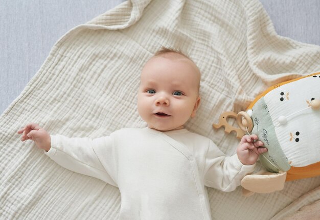 Pasgeboren peuterjongen liegt en speelt met educatief speelgoed. gelukkig moederschap en vaderschap. kraamkliniek en kliniek. vader en moeder dag. ontwikkeling in de vroege kinderjaren.