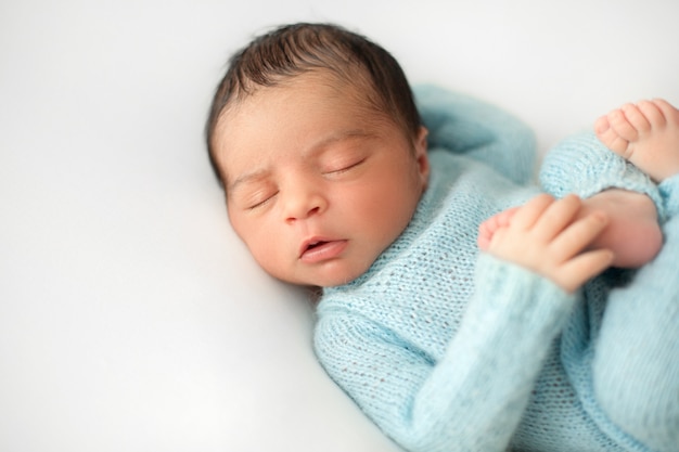 Pasgeboren slapende babyjongen op witte stoel in schattige blauwe haakwerk